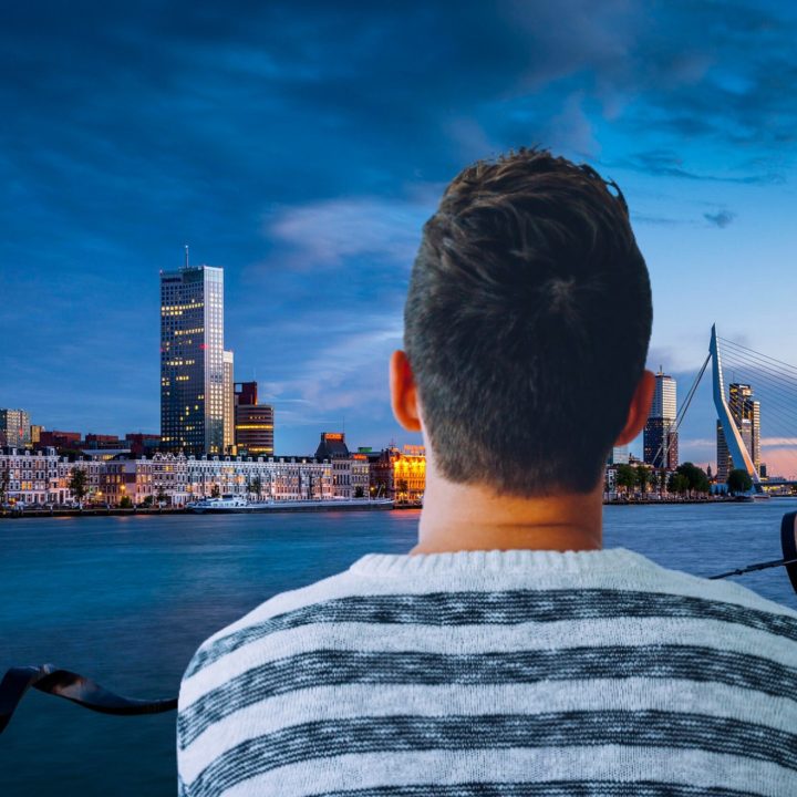 primo piano di un ragazzo di spalle che guarda, di sera, lo skyline di una città