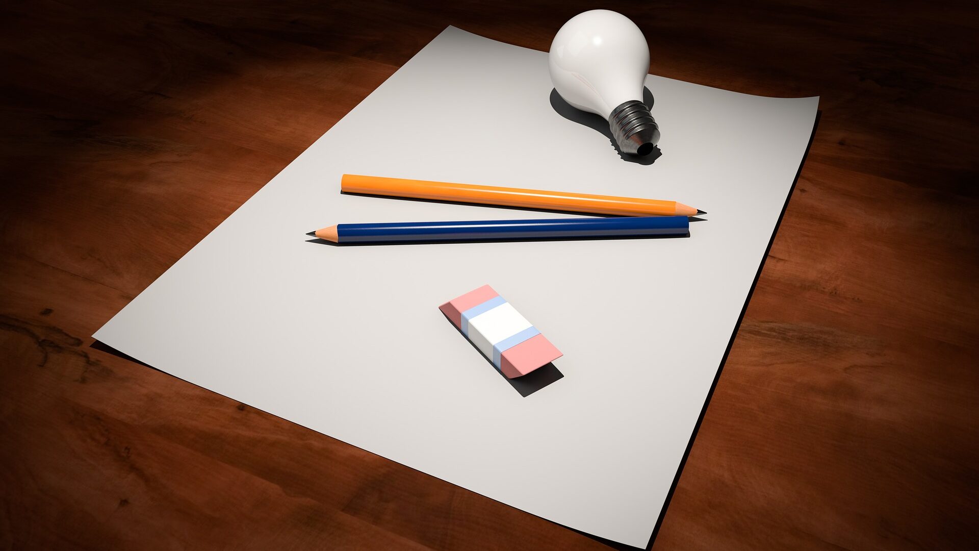 foglio bianco su una scrivania di legno con sopra due matite, una gomma e una lampadina