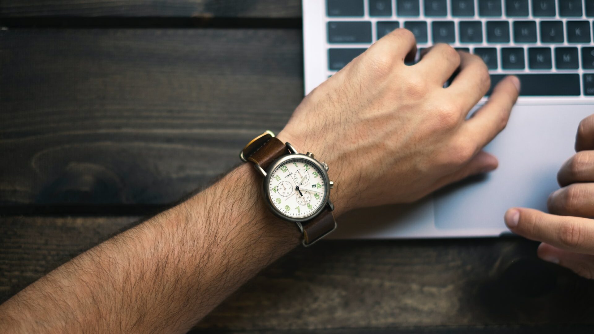 Braccio con orologio al polso che scrive al computer